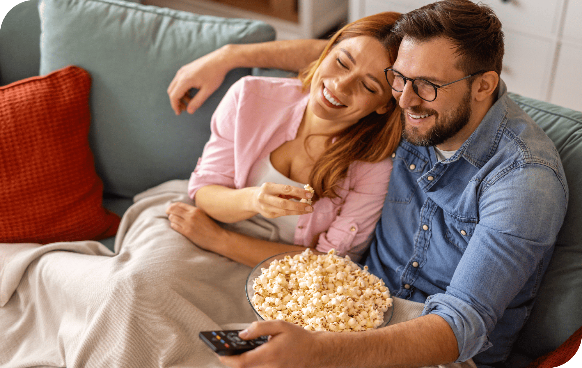 Couple smiling on couch enjoying popcorn watching tv. Couple smiling on couch enjoying popcorn watching tv.