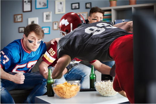 Guys watching football with a football player coming out of the tv.