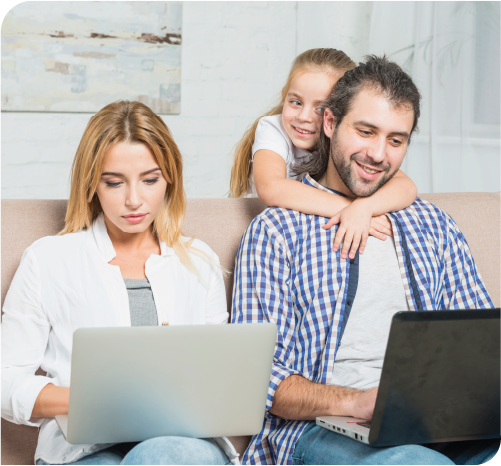 Couple using laptops on a couch with daughter's arms around her dad.. Couple using laptops on a couch with daughter's arms around her dad..