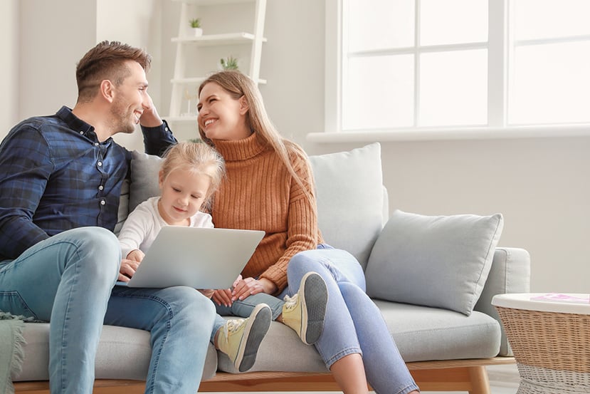 Family talking on couch with toddler playing on tablet. Family talking on couch with toddler playing on tablet.