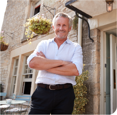 Smiling building owner standing in front of his property with arms crossed. Smiling building owner standing in front of his property with arms crossed.