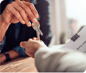 Two people handing keys to a building to one another. Two people handing keys to a building to one another.