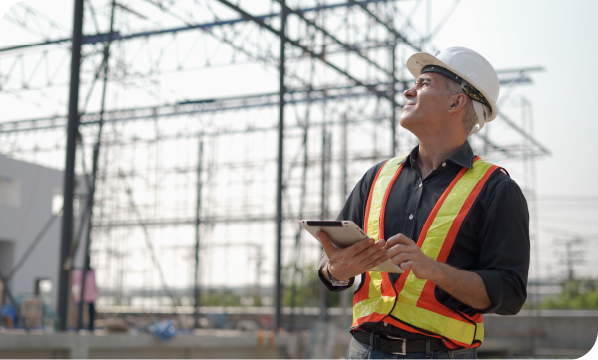 Construction worker observing a project with a tablet in his hand.