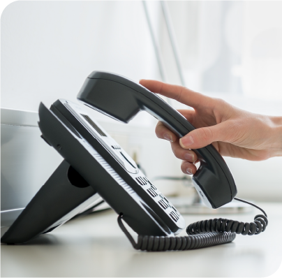 Woman's hand picking up a business phone from its receiver.