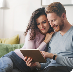 Couple looking at a tablet on a couch. Couple looking at a tablet on a couch.
