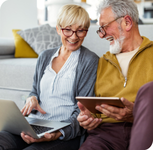 Older couple smiling as they use this laptop and tablet. Older couple smiling as they use this laptop and tablet.