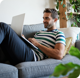 A man relaxing on a couch with a laptop in his lap. A man relaxing on a couch with a laptop in his lap.