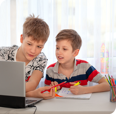 Two boys looking at laptop and drawing with colored pencils Two boys looking at laptop and drawing with colored pencils
