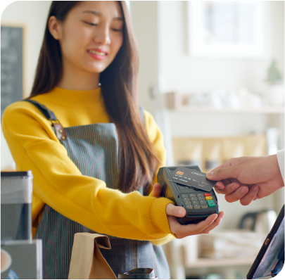 A young woman cashier accepting payment on a wireless card reader.
