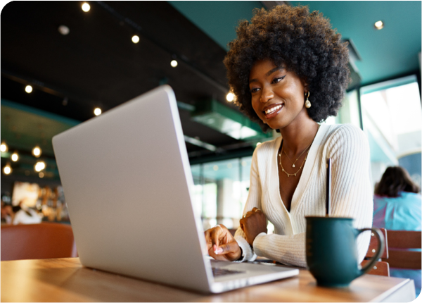 Diverse businessman smiling on laptop with coffee mug at cafe Diverse businessman smiling on laptop with coffee mug at cafe